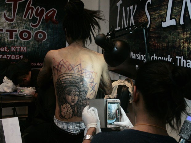 Tatuador fotografa um de seus clientes durante a Convenção Internacional de Tatuagem do Nepal (Foto: Kyle Knight /AFP)