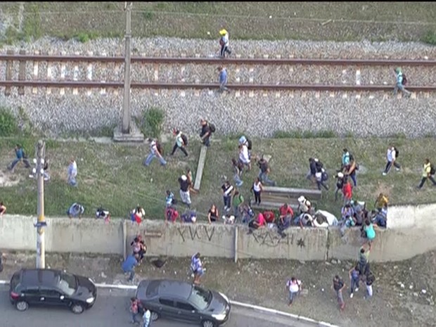 Passageiros pulam muro após trem parar entre estações da CPTM  (Foto: Reprodução/TV Globo)