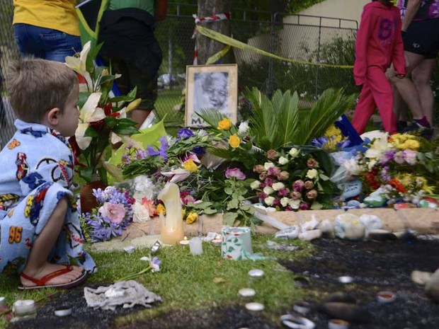 Um menino para diante de um santuário em homenagem a Mandela, na frente da casa do lide sul-africano, em Joanesburgo. (Foto: Grant Lee Neuenburg / Reuters)