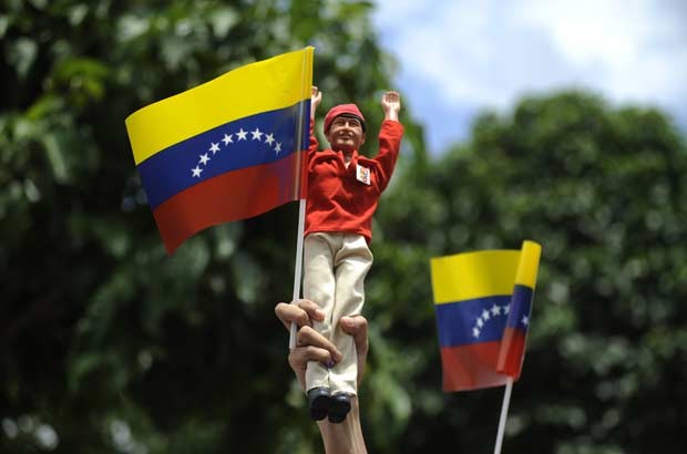 Partidário de Chávez levanta boneco do presidente durante o período de votação nesta segunda-feira (8) (Foto: AP)