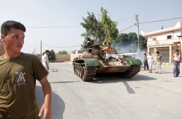 Integrantes do exército rebelde comemoram em tanque tomado de forças do governo em Anadan, a 5km de Aleppo (Foto: Junot Diaz / AFP)