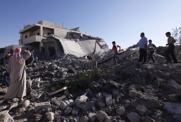 Moradores observam construção destruída após ataque ao norte de Aleppo nesta segunda-feira (3) (Foto: Reuters)