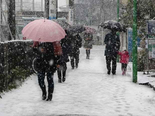 Pedestres caminham sobre a neve em estação de trem em Tóquio nesta sexta-feira (30) (Foto: YOSHIKAZU TSUNO/AFP)