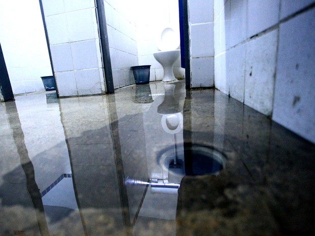 Diretora da escola diz que há um retorno na água e, por isso, os banheiros ficam alagados (Foto: Jonathan Lins/G1)