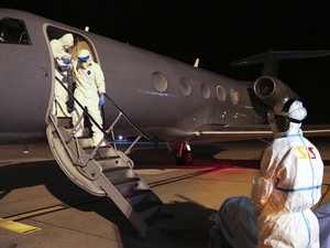 Amparado, o médico cubano Gélix Báez Sarria deixa o avião no qual foi transportado de Serra Leoa à Suíça para tratamento de ebola (Foto: AP Photo/Aeroport International de Geneve)
