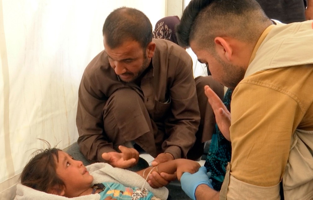 Menina é confortada pelo pai enquanto recebe atendimento médico no campo no campo de refugiados Hasansham U2, no norte do Iraque  (Foto: Balint Szlanko/ AP)
