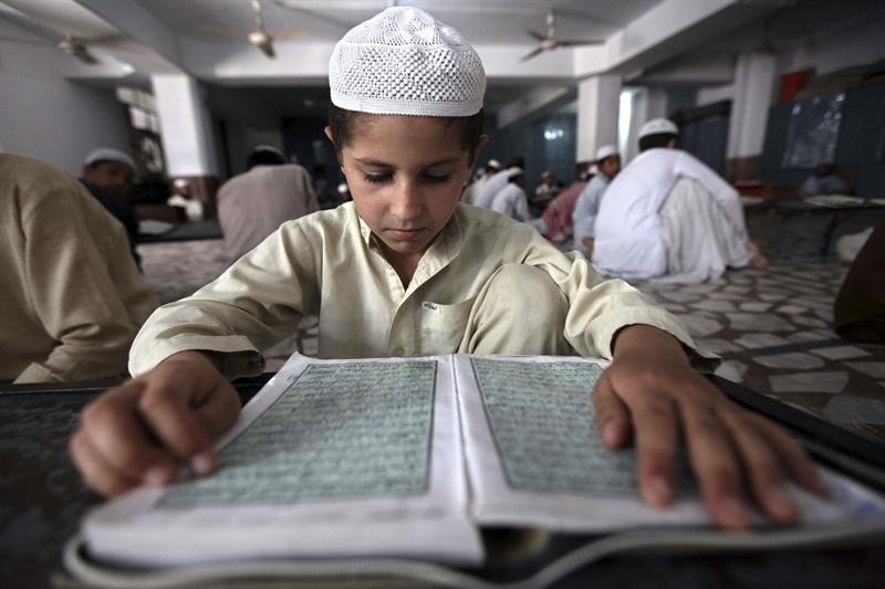Numa escola de Peshawar, criança paquistanesa lê escritos do Alcorão, o livro sagrado do Islã, no primeiro dia do Ramadã