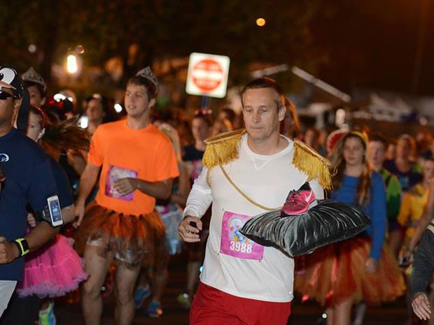 Participante vestido de príncipe corre com tênis em almofada, como se fosse sapatinho de cristal (Foto: Walt Disney World/Divulgação)