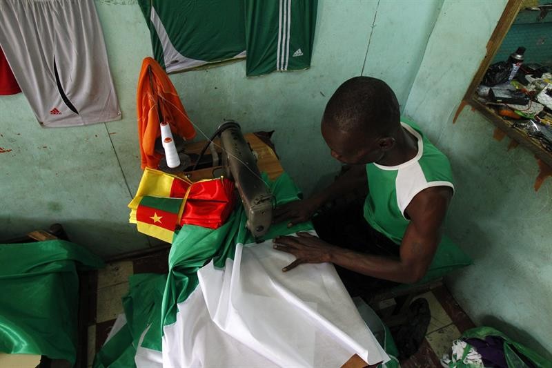 Em Abijão, na Costa do Marfim, costureiro confecciona bandeira do país para vender a torcedores durante dos jogos da Copa do Mundo