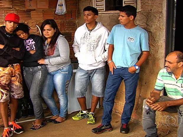Ao lado do pai de rapaz desaparecido, amigos lamentam a morte de Neylor Carneiro, em Aparecida de Goiânia, Goiás (Foto: Reprodução/TV Anhanguera)