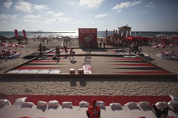 Jogador lança dado em tabuleiro gigante de gamão em praia na cidade israelense de Tel Aviv nesta segunda-feira (2). O tabuleiro, considerado o maior do país, foi colocado na praia como parte de um festival (Foto: Nir Elias/Reuters)