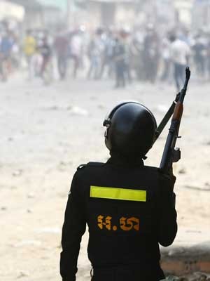 Policial segura um rifle durante distúrbios no Camboja. (Foto: Heng Sinith / AP Photo)