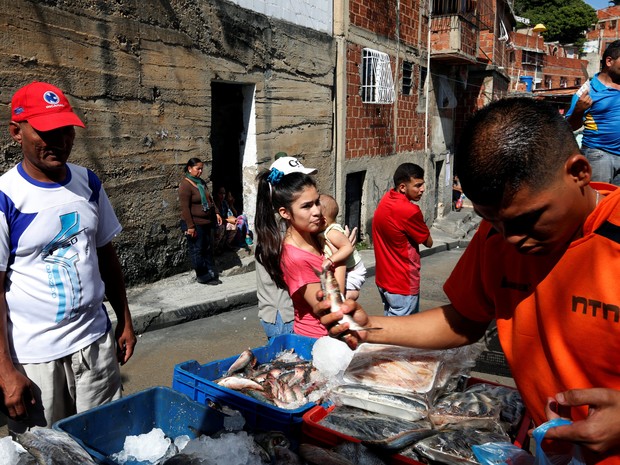 Homem vende peixes em favela de Caracas, neste sábado (9) (Foto: REUTERS/Carlos Jasso)