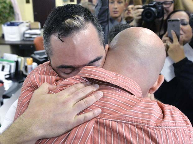 James Yates e William Smith Jr. se abraçam após receber licença de casamento em cartório em que tabeliã negava tramitar pedido, no condado de Rowan, nesta sexta-feira (4) (Foto: AP Photo/Timothy D. Easley)