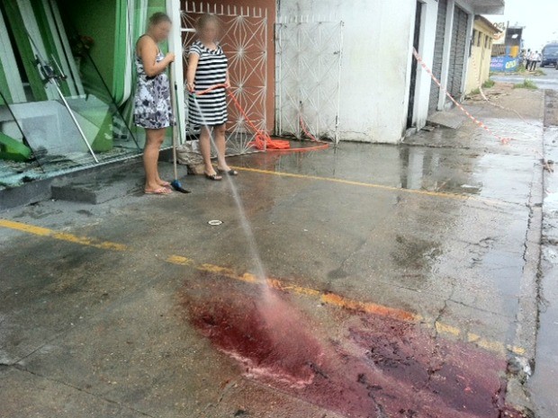 Senhora lava sangue de vitima de homicídio ocorrido na madrugada desta sexta (19) em Manaus (Foto: Ana Graziela Maia/G1 AM)