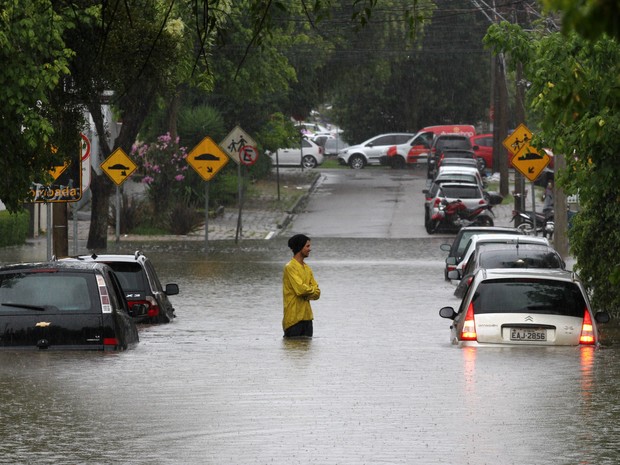 Um homem é visto em meio a carros submersos durante enchente em rua do bairro Alto da XV, em Curitiba. Segundo o Instituto Meteorológico do Paraná até às 15h15 choveu o equivalente a 38% da chuva prevista para fevereiro (Foto: Paulo Lisboa/Brazil Photo Press/Estadão Conteúdo)