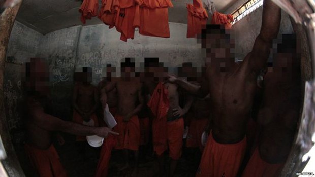 Em uma das celas, presos usam suas próprias camisetas para secar chão molhado (Foto: BBC Brasil)