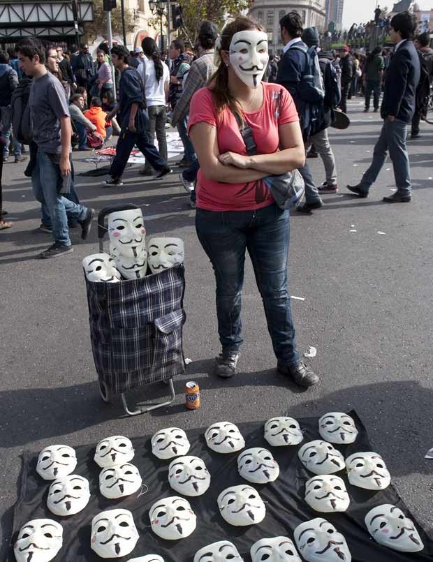Vendedora aproveitou manifestação para vender máscaras de personagem do filme 'V de Vingança' (Foto: Hector Retamal / AFP)