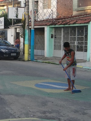 Jovem limpa o asfalto para concluir decoração em ritmo de copa do mundo (Foto: Denison Roma / Globoesporte.com)