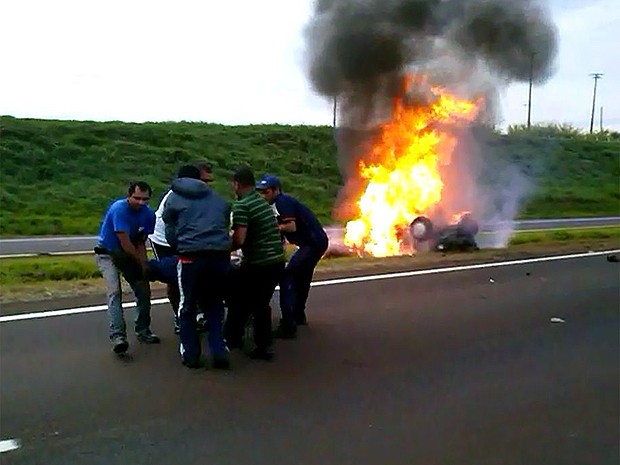 Motorista é retirado de perto do carro em chamas por pessoas que passvam pelo local. (Foto: Reprodução/EPTV)