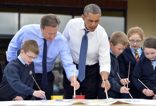 O presidente dos EUA, Barack Obama, ao lado do premiê britânico, David Cameron, pinta com crianças em visita a escola em Enniskillen, na Irlanda do Norte, à margem da cúpula do G8, nesta segunda-feira (17) (Foto: AFP)