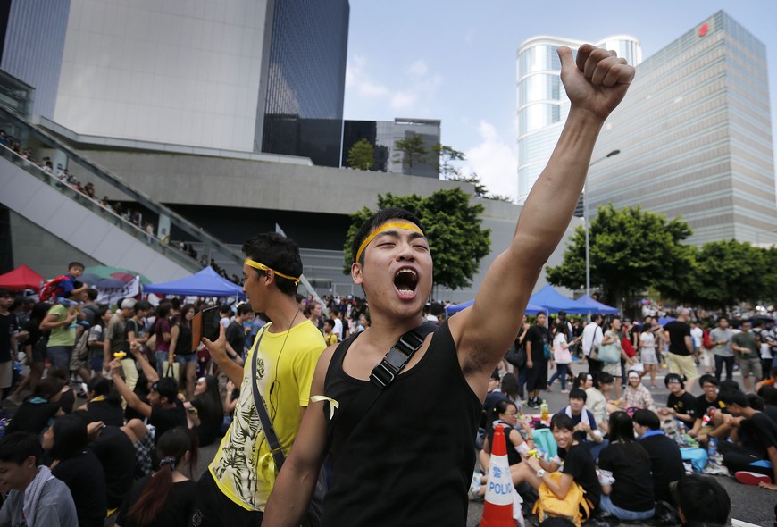 A pro-democracy activist shouts slogans on a street near the government headquarters where protesters have made camp, Wednesday, Oct. 1, 2014 in Hong Kong. Holiday crowds swelled into the tens of thousands as student leaders met with other pro-democracy p