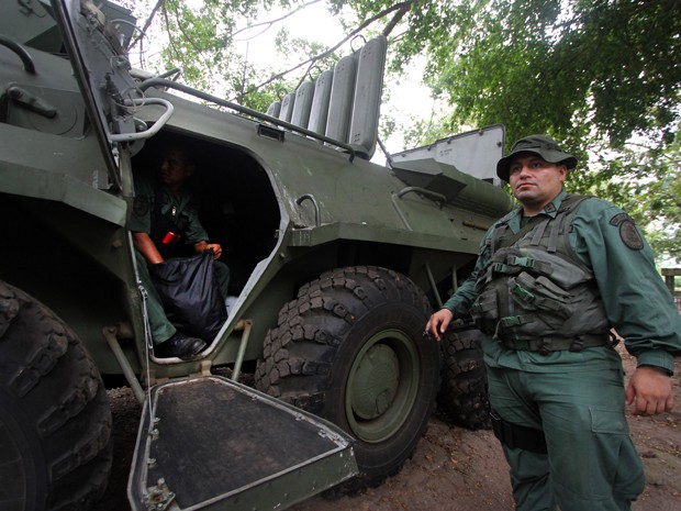 Membro do exército da Venezuela posa ao lado de veículo militar na cidade de San Cristobal, no sábado (14), durante exercícios de treinamento (Foto: AFP Photo/George Castellano)