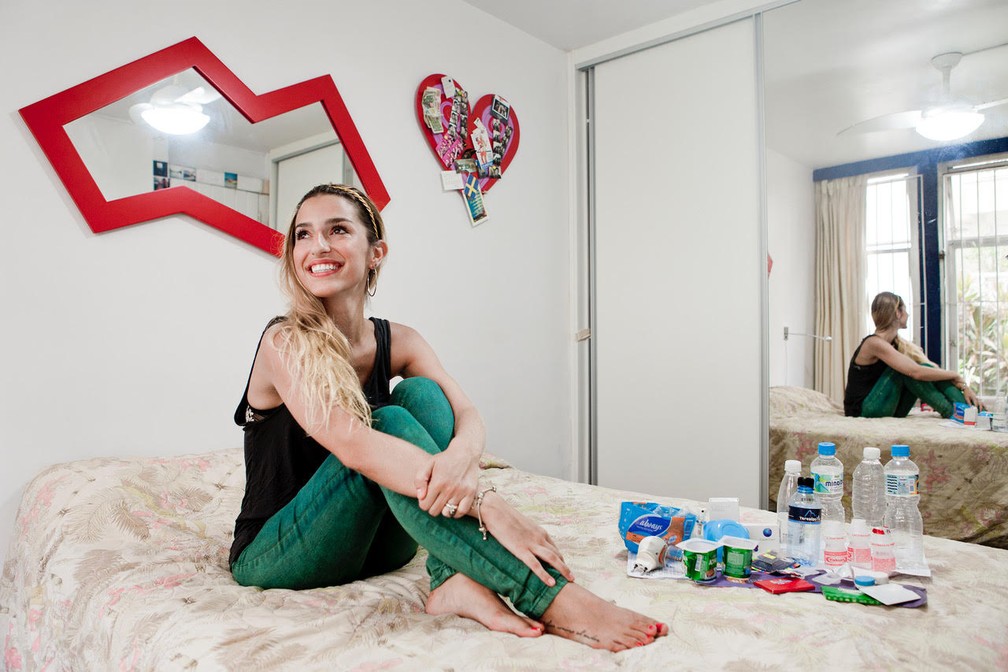 Mulher posa com embalagens de iogurtes, águas e outros resíduos (Foto: Rafael Duarte/G1)