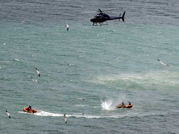 Policiais patrulham e até disparam contra um tubarão nas águas da praia de Muriwai Beach. (Foto: Ross Land / AP Photo)