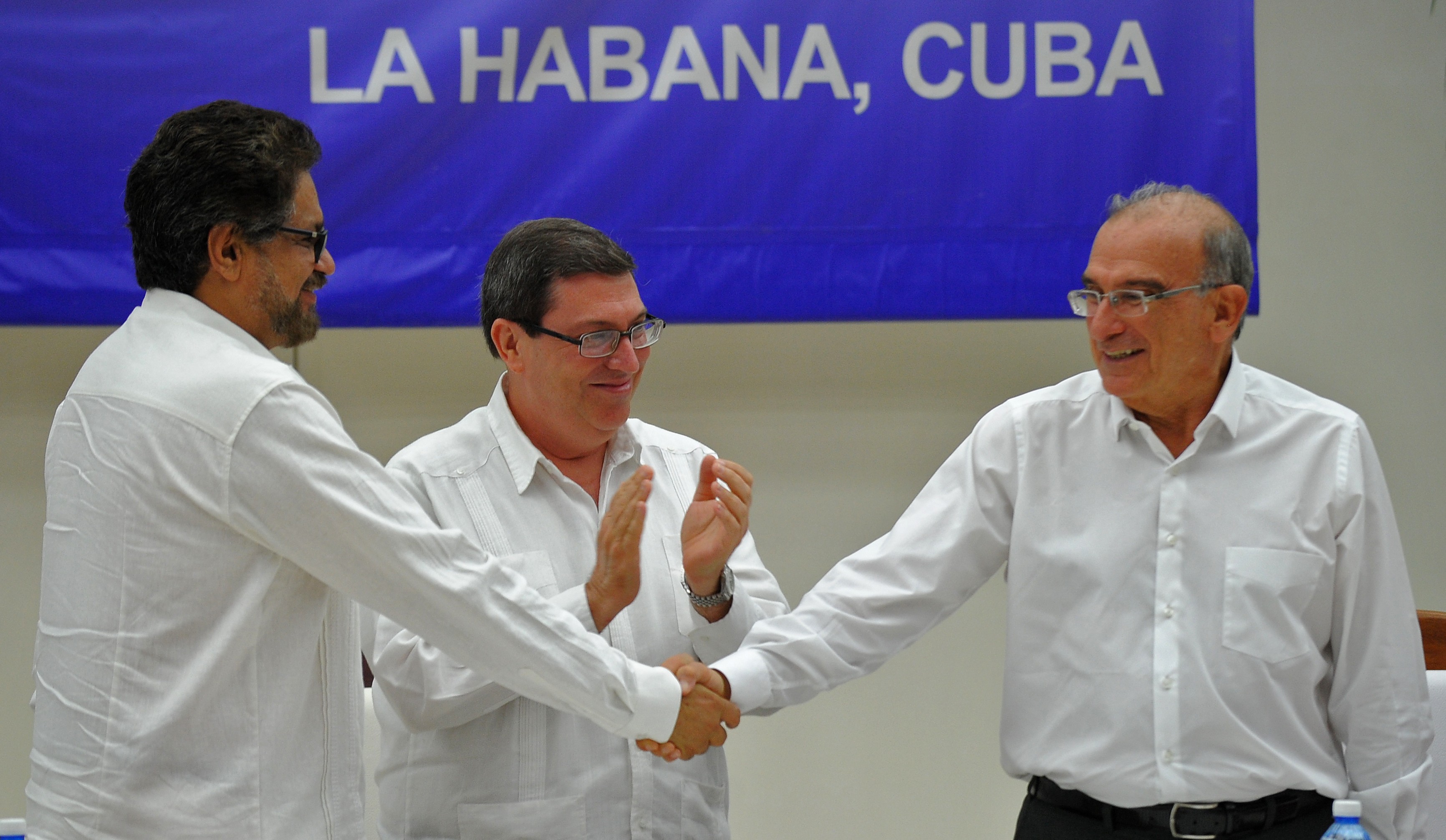 O comandante das Farc Iván Marquéz (esquerda) e o chefe da delegação de paz colombiana Humberto de la Calle (direita) apertam as mãos nesta quarta-feira (24) em Havana, Cuba, após assinarem o acordo definitivo de paz na Colômbia (Foto: YAMIL LAGE / AFP)