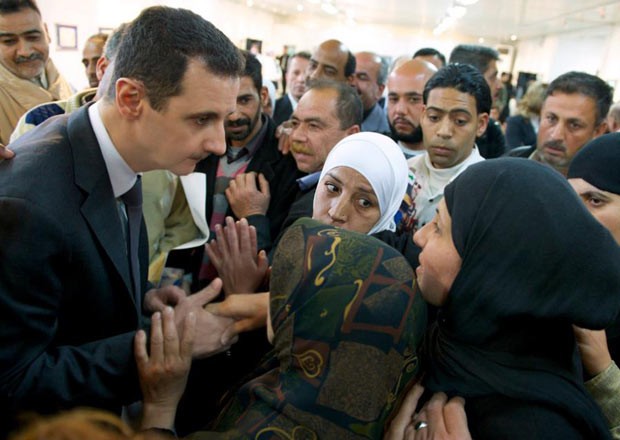 O presidente da Síria, Bashar al-Assad, conversa com mulheres em visita-surpresa à escola de Belas Artes de Damasco, em foto divulgada nesta quarta-feira (20) (Foto: AFP)