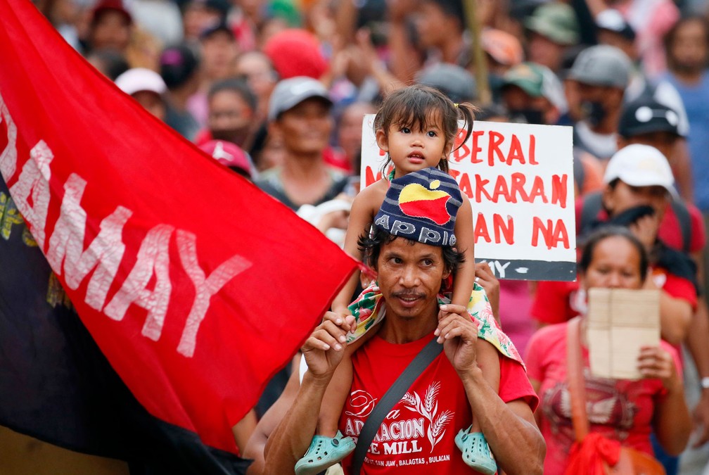 Pai carrega filha nos ombros durante protesto no Dia do Trabalhador em direção ao palácio presidencial em Manila, nas Filipinas, nesta segunda-feira, dia 1º de maio de 2017 (Foto: Bullit Marquez/AP)