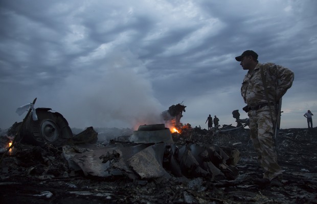 Oficiais observam os destroços do avião da Malaysia Airlines que caiu perto no leste da Ucrânia. A aeronave seguia de Amsterdã para Kuala Lumpur (Foto: AP Photo/Dmitry Lovetsky)