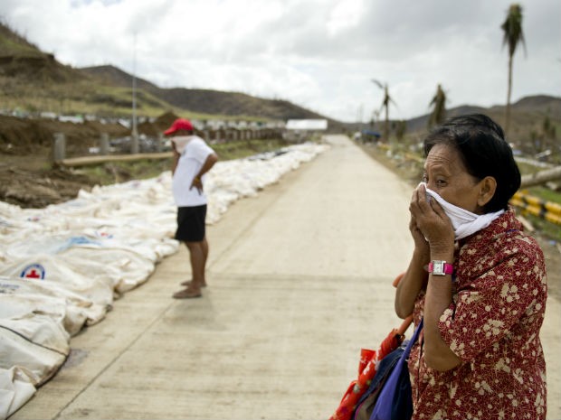 Mulher tampa o nariz diante de 170 corpos deixados à beira da estrada em Tacloban. (Foto: Odd Andersen/AFP)