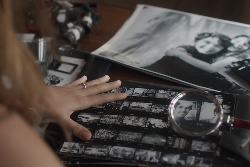 Alice se detém comparando as fotos de Renato e Lucas (Foto: TV Globo)