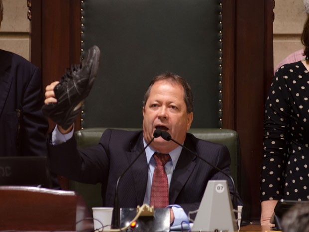 O vereador Chiquinho Brazão (PMDB) mostra sapato arremessado por manifestantes durante abertura da sessão de depoimentos na CPI dos Ônibus na Câmara Municipal do Rio de Janeiro (Foto: EBRS JR./Estadão Conteúdo)