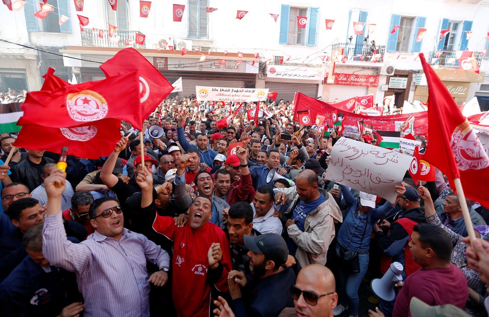 Membros da União Geral dos Trabalhadores Tunisiana (UGTT, na sigla em inglês) seguram cartazes e bandeiras durante marcha para marcar do Dia do Trabalhador na Tunísia, nesta segunda-feira, dia 1º de maio de 2017 (Foto: Zoubeir Souissi/Reuters)
