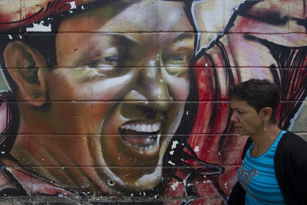 Mulher passa por mural representando o presidente venezuelano Hugo Chávez, nesta quarta-feira (9), em Caracas (Foto: AFP)