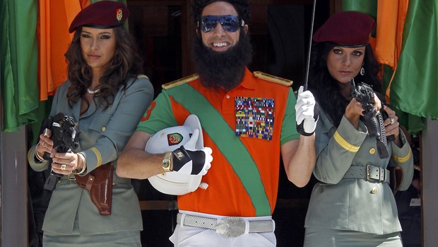 Ao lado de guarda-costas femininas, Sacha Baron Cohen sorri vestido de ditador em chegada ao Festival de Cannes (Foto: Jean-Paul Pelissier/Reuters)