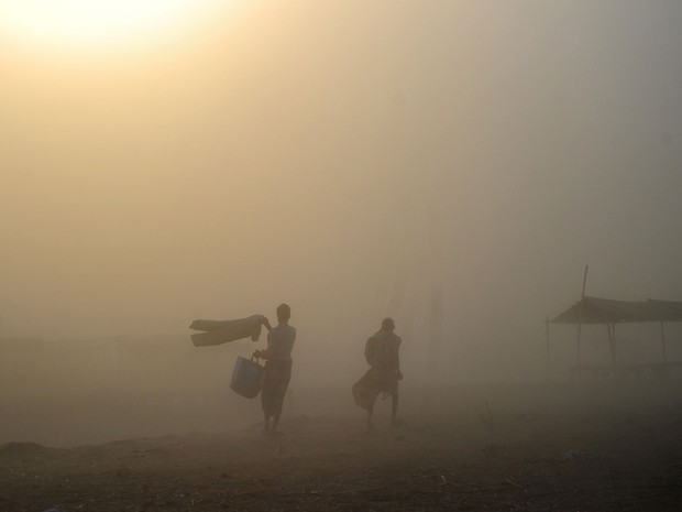 Homens caminham em meio a tempestade de poeira em Allahabad, na Índia (Foto: Sanjai Kanojia/AFP)