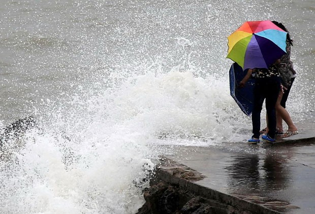 Mulheres veem onda forte na costa de Haikou, na China (Foto: AFP) Mulheres veem onda forte na costa de Haikou, na China (Foto: AFP)