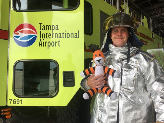 Bombeiro segura o tigre de pelúcia durante seu tour pelo aeroporto (Foto: Reprodução/Facebook/Tampa Internacional Airport)