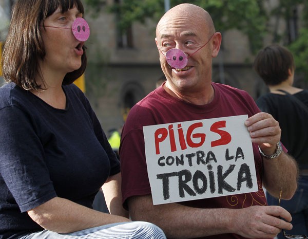 Em Madri, manifestantes levam cartaz que diz Piigs contra a "troica", se referindo aos países europeus com maiores problemas econômicos: Portugal, Irlanda, Itália, Grácia e Espanha. (Foto: Quique Garcia/AFP PHOTO )