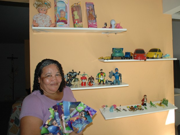 A Mãe Social Jacinta Firmino posa com fotos e brinquedos de seus nove filhos na sala da sua Casa Lar (Foto: Andréia Martins/G1)