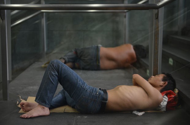 Moradores tentam se abrigar do calor em entrada de estação de metrô nesta quarta-feira (31) em Xangai (Foto: Peter Parks/AFP)