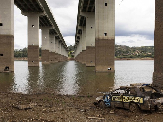 Carcaça de um carro pichado com a frase 'Bem-vindo ao Deserto da Cantareira' é visto sob uma ponte que cruza trecho de reserva da Cantareira em Nazaré Paulista (SP) (Foto: Roosevelt Cassio/Reuters)