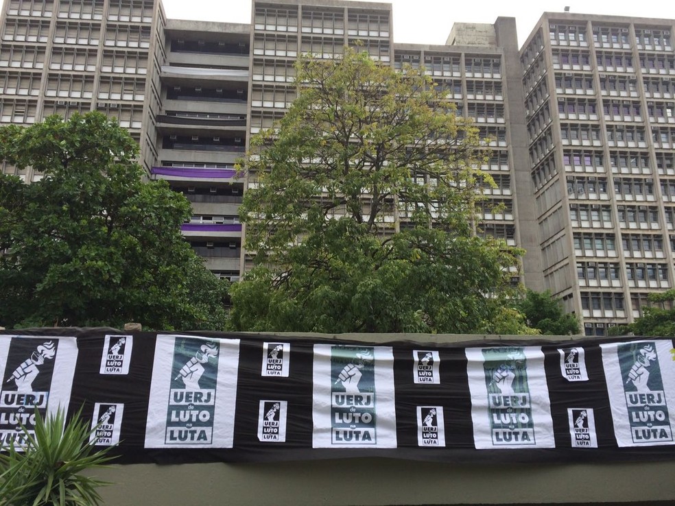 Fachada da Uerj, com grades cobertas por pano preto e com cartazes incentivando os estudantes e docentes e lutar pela instituição  (Foto: Cristina Boeckel/ G1)