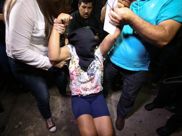 Empregada doméstica foi carregada pela polícia com pano no rosto (Foto: Tiago Queiroz/Estadão Conteúdo)