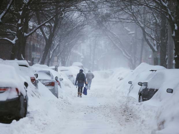 Pedestres andam por ruas com carros cobertos de neve nesta segunda-feira (9) em Cambridge, Massachusetts (Foto: REUTERS/Brian Snyder)