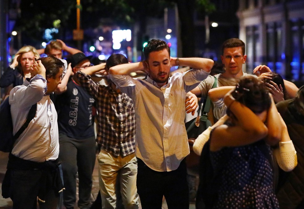 Pessoas saem da área próxima a London Bridge com as mãos na cabeça (Foto: REUTERS/Neil Hall )